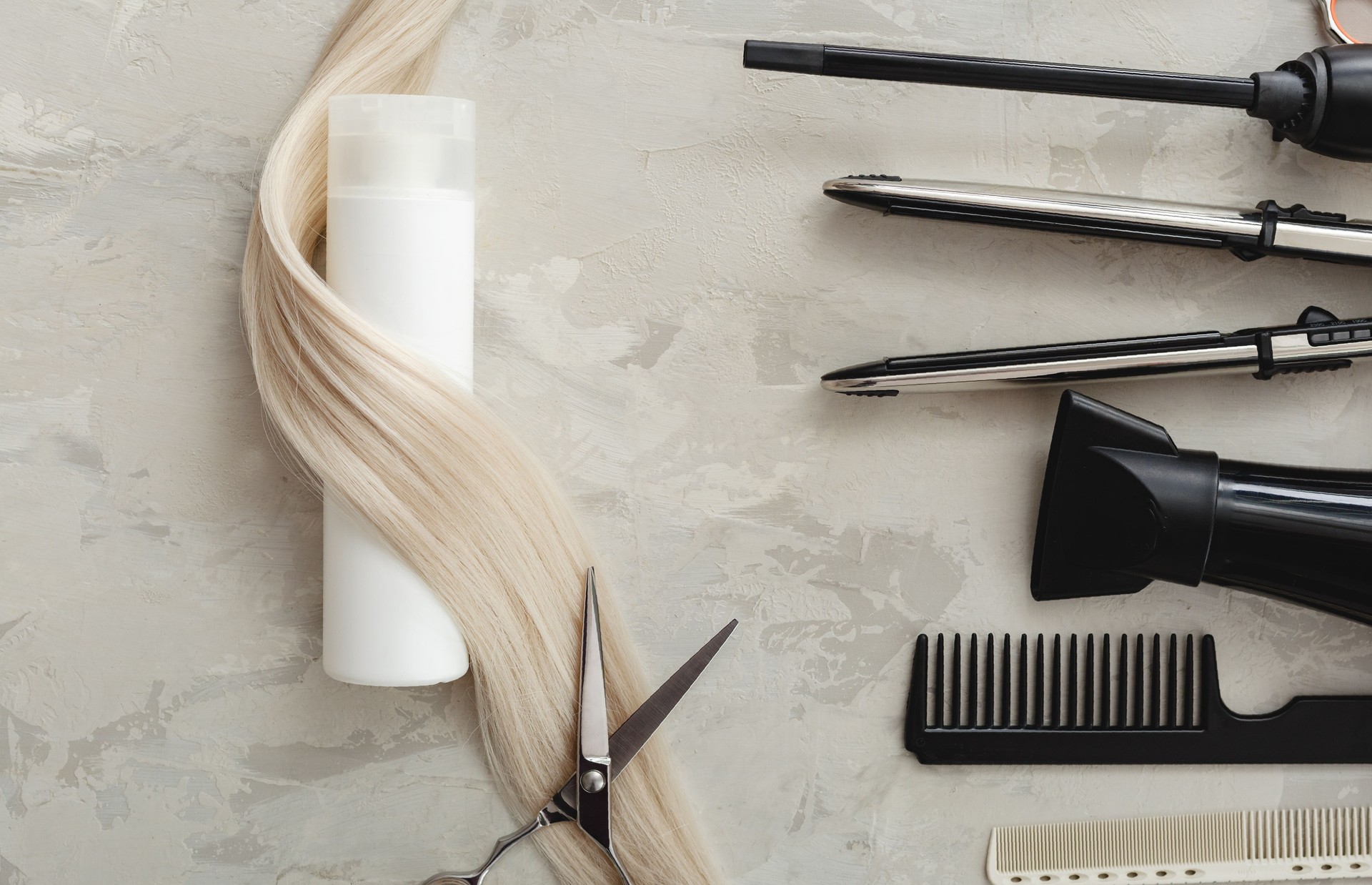 Composition plate de pose avec des outils de coiffeur et bouteille blanche de produit cosmétique, cheveux blonds sur le fond gris. Maquette de shampooing. Espace pour la conception. Service de coiffure. Concept de cosmétiques naturels.